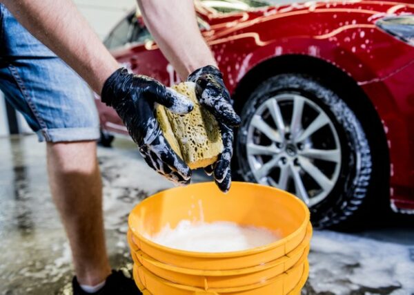pracownik myjacy czerwony samochod gabka na myjni samochodowej 179755 9834